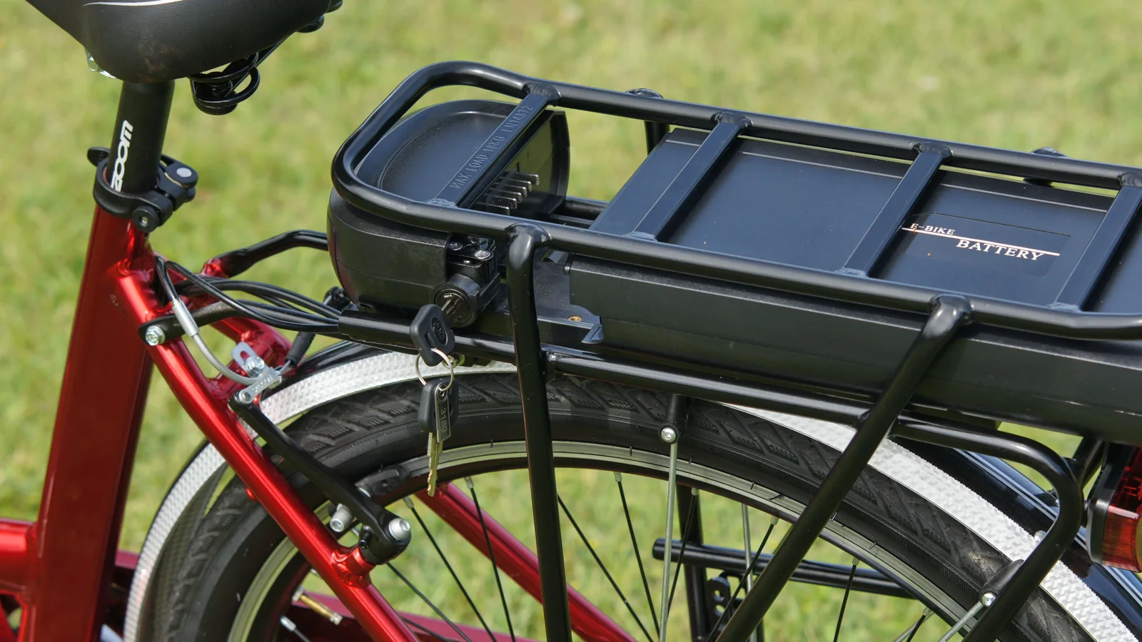 E-Bike-Akku auf dem Gepäckträger eines roten Fahrrads
